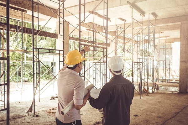 Two men in hard hats discussing the building work of the building they're in