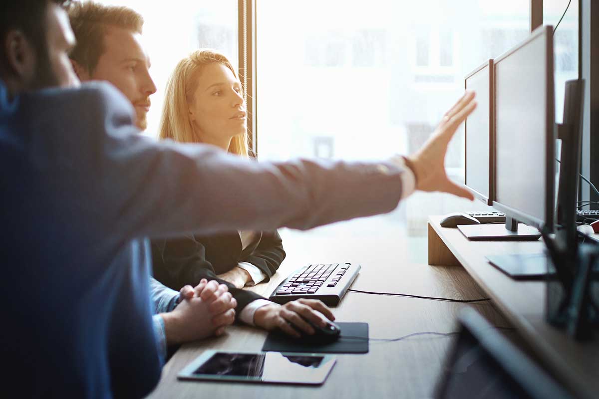 3 people at work discussing what's on the computer in front of them