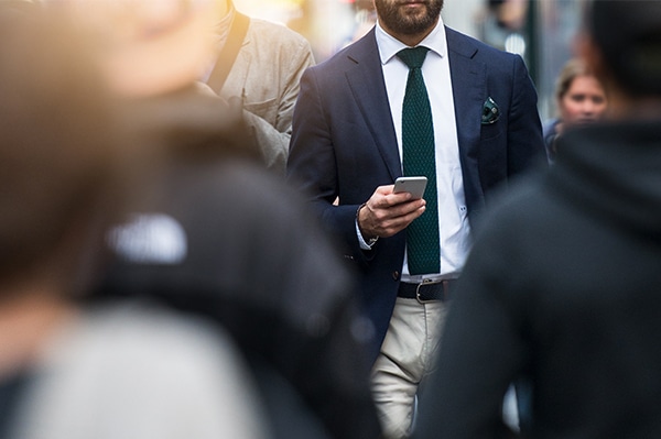 A man walking on a busy street and looking at his smartphone