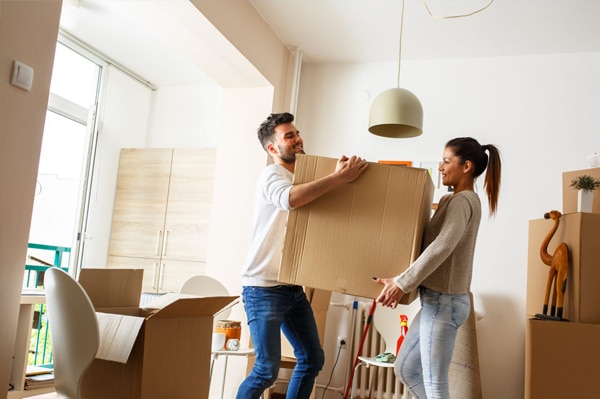 A man and woman moving a box into their new home