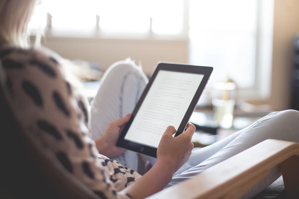 A woman relaxing at home reading an ebook on an ipad