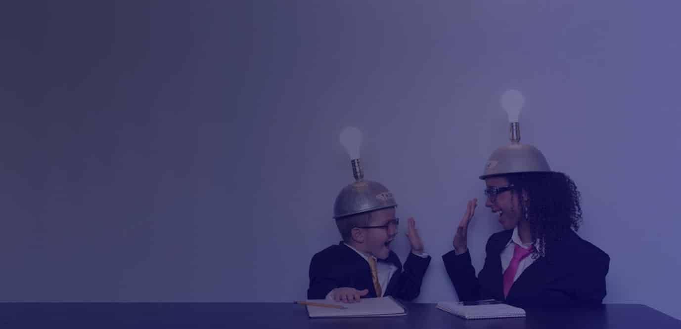 A boy and a girl in suits and ties wearing lightbulbs on their heads and high-fiving each other