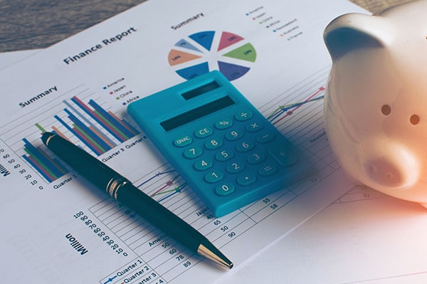 A close up of a financial report, calculator, and piggy bank