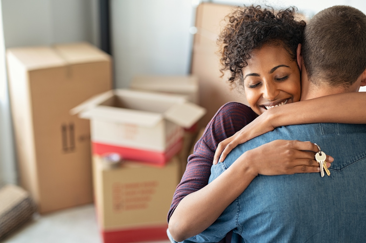 A man and woman hugging as they hold the keys to their new home
